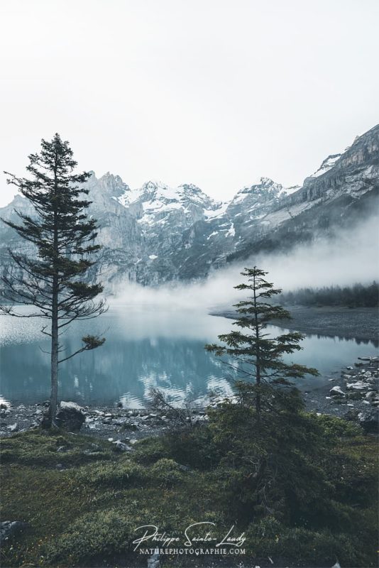 Le brouillard descend sue l'Deux pêcheurs sur une barque au milieu du lac Oeschinensee en Suisse